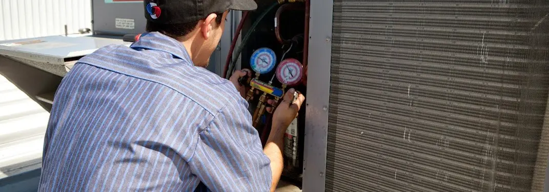 HVAC technician servicing a condenser unit in Kalkaska